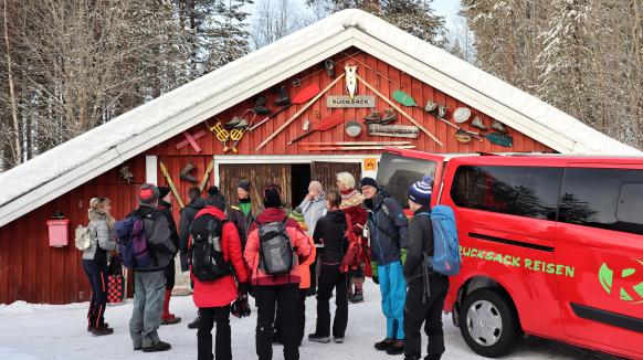 Gäste im Wintercamp Idre vor dem Schuppen und einem Rucksack Reisen Auto, bereit für das Tagesprogramm