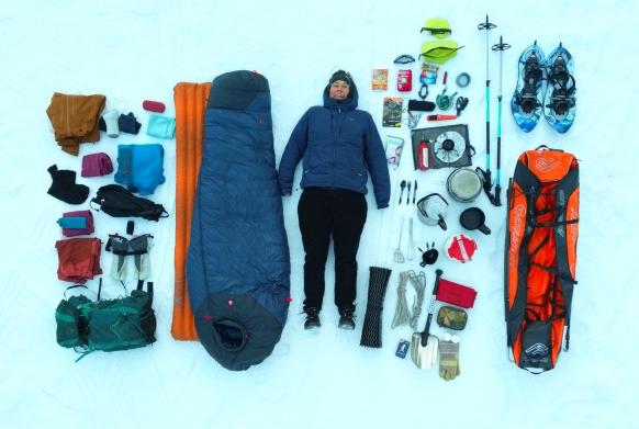 Frau liegt im Schnee, neben ihr liegt sie benötigte mehrtägige Schneeschuhwanderung