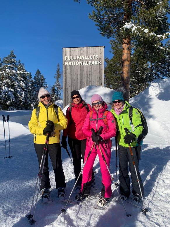 4 Schneeschuhwanderinnen stehen vor Schild des Fulufjäll Nationalparks