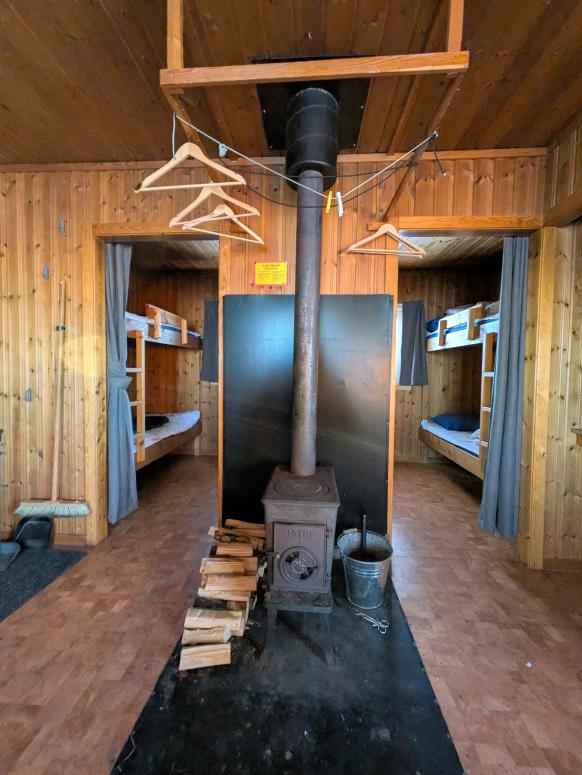 Hütte von innen mit 2 Schlafkabinen und Ofen im Gemeinschaftsraum