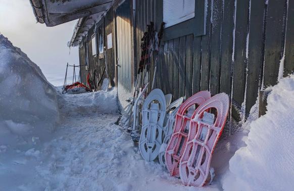 Schneeschuhe stehen vorm Eingang einer Hütte